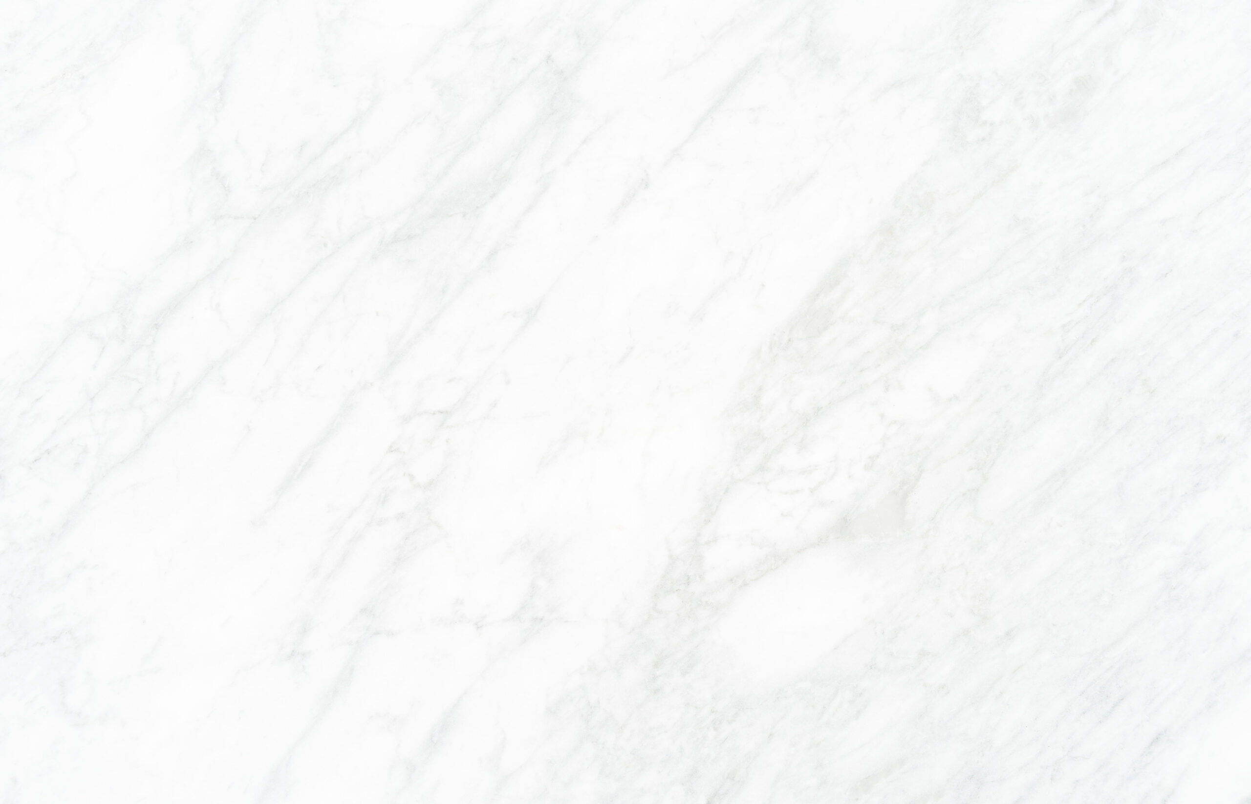 Smooth white marble surface with subtle gray veining patterns running diagonally across. The texture is polished, reflecting light and giving a clean, elegant appearance.